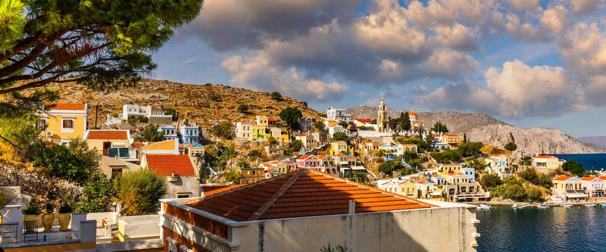 A coastal town with colorful buildings, a prominent church with a bell tower, and a clear view of the sea.