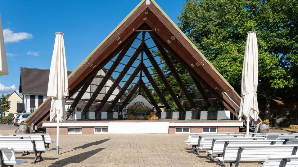 A pavilion with a triangular roof and benches in front.