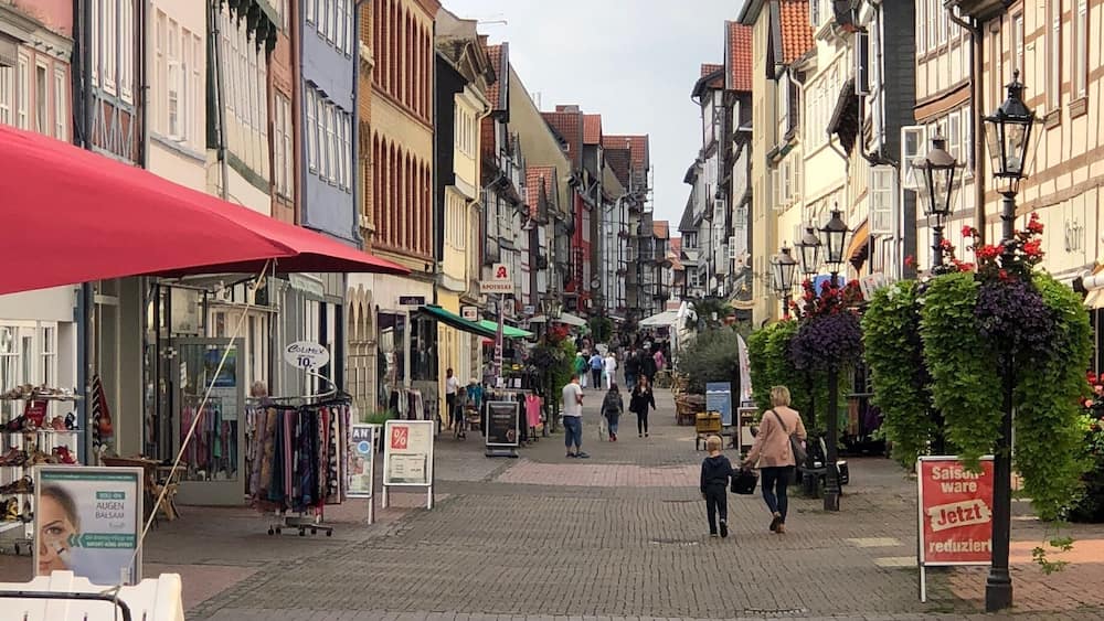 A cobblestone street lined with colorful buildings, a bicycle with a basket, and pedestrians.