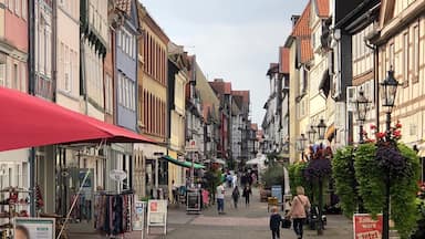 A cobblestone street lined with colorful buildings, a bicycle with a basket, and pedestrians.