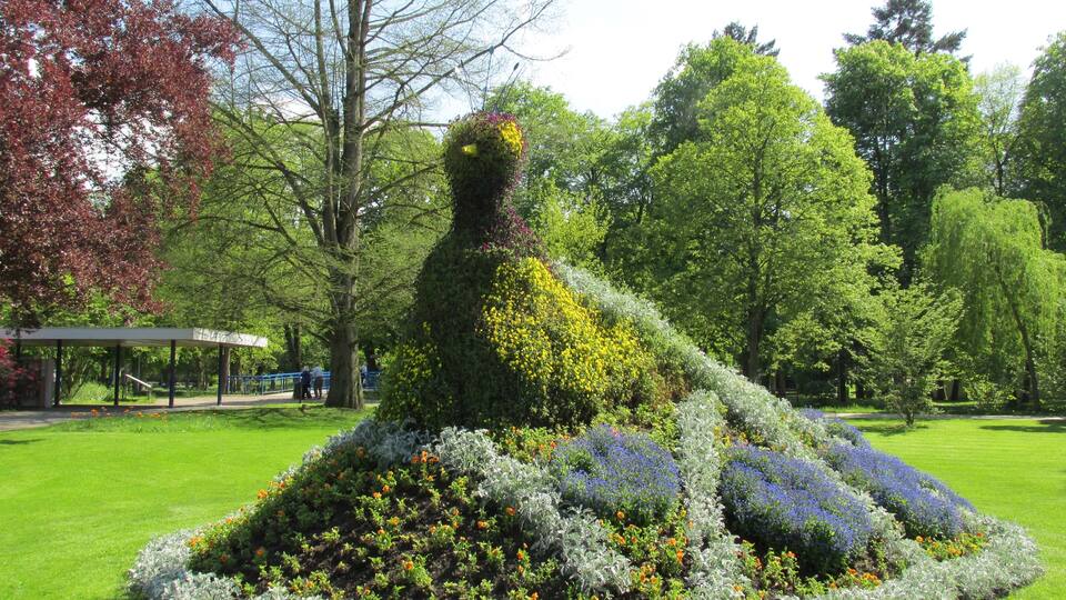 A garden sculpture of a woman surrounded by flowers.