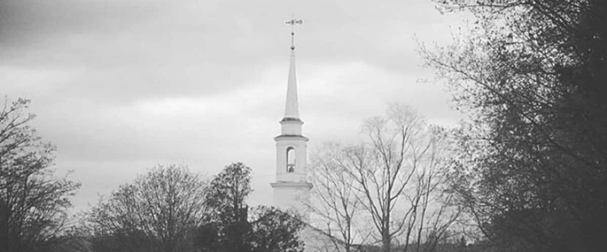 A cemetery with a church steeple in the background.