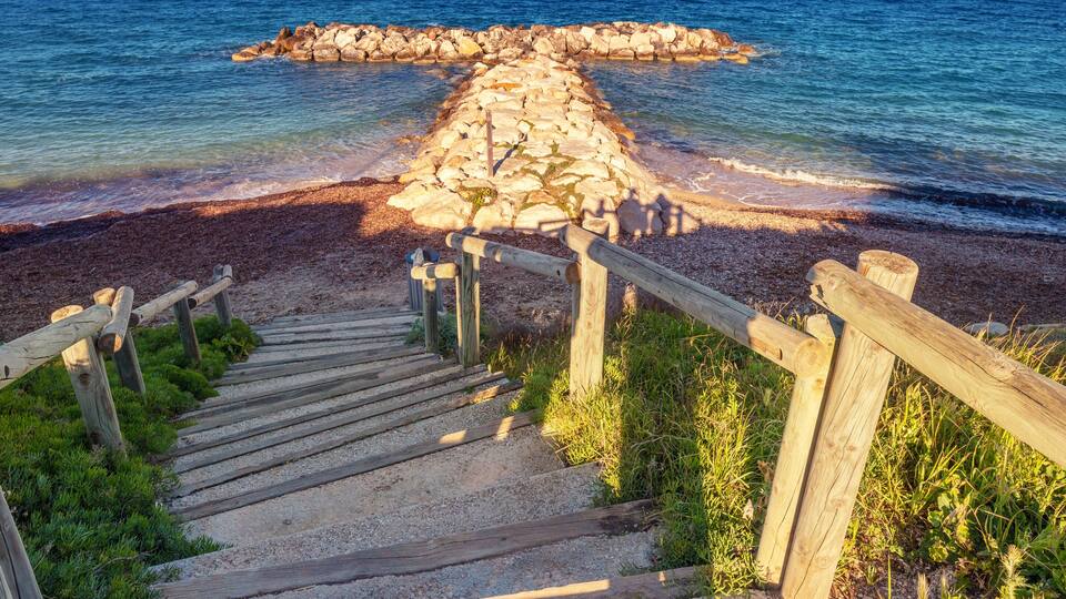 A wooden staircase leading to a rocky outcrop by the sea.