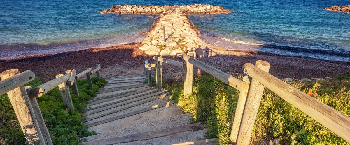 A wooden staircase leading to a rocky outcrop by the sea.