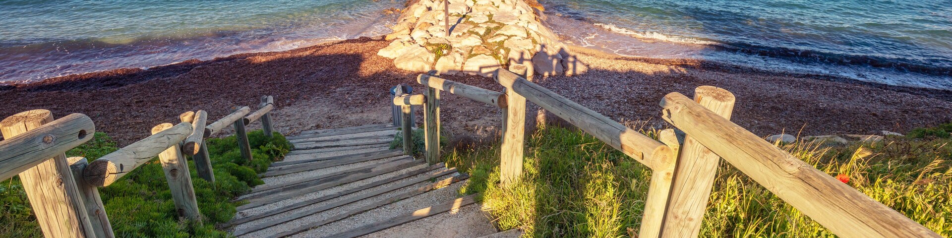 A wooden staircase leading to a rocky outcrop by the sea.