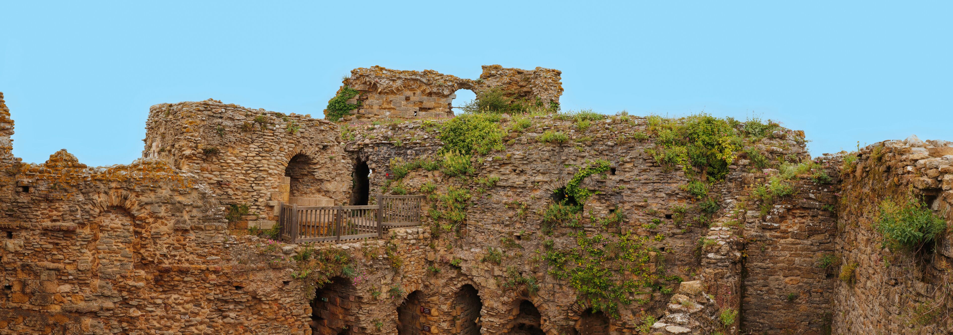 Ancient stone ruins with arches and overgrown vegetation.