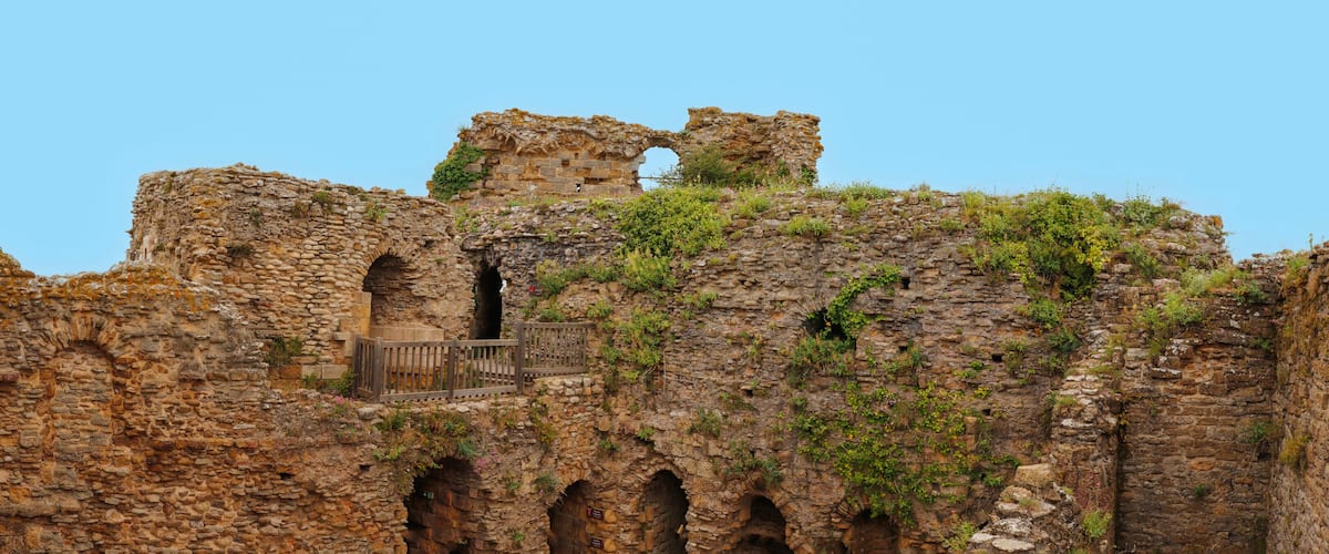 Ancient stone ruins with arches and overgrown vegetation.