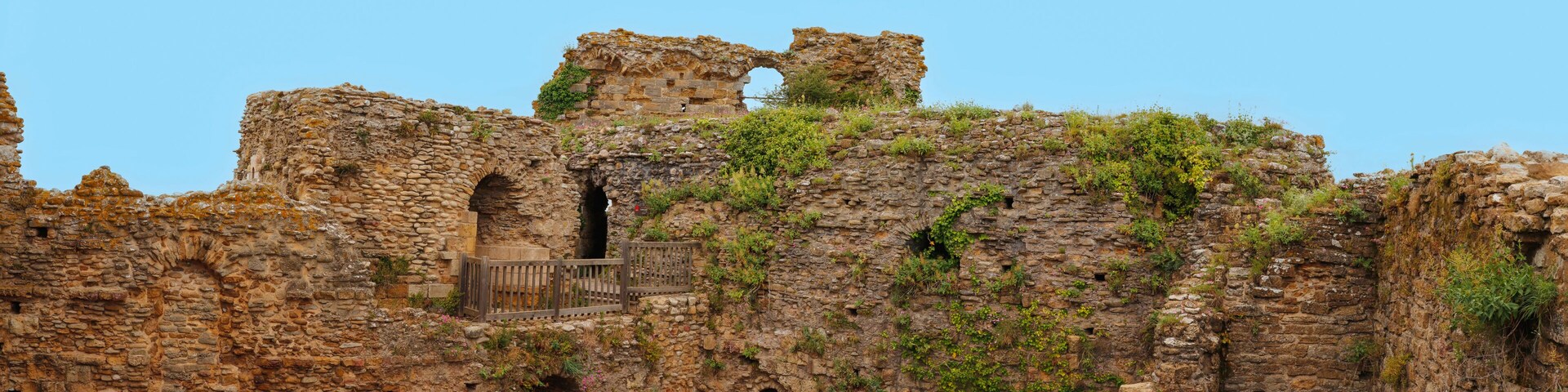 Ancient stone ruins with arches and overgrown vegetation.