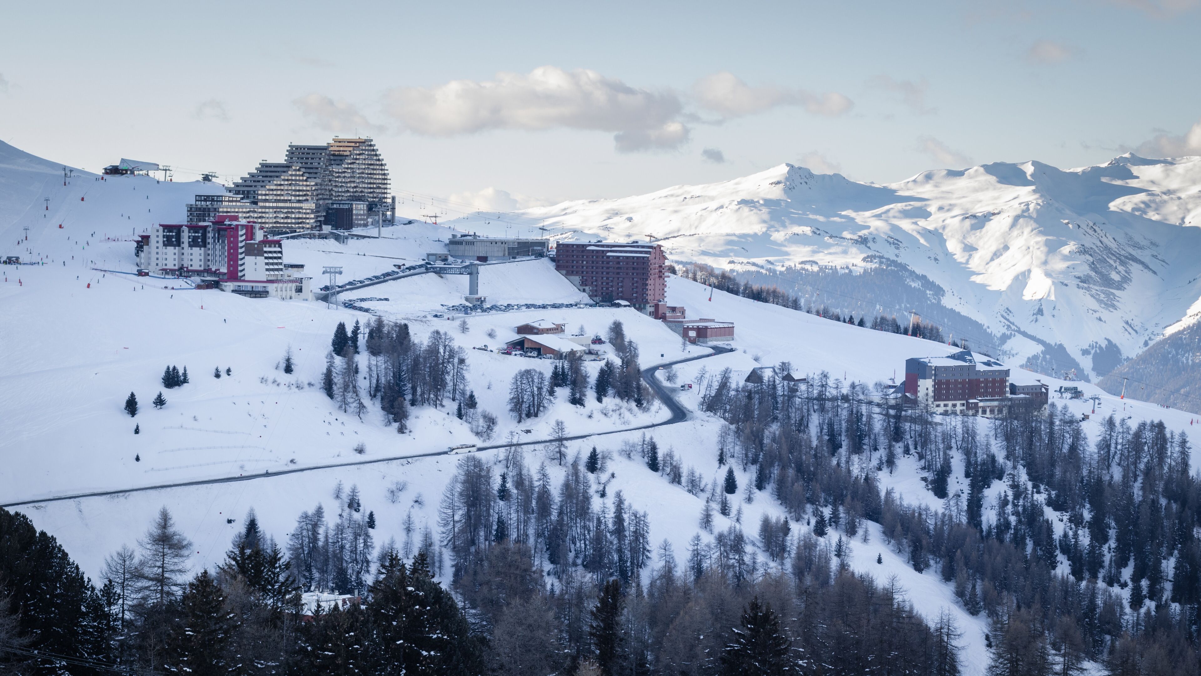 A snow-covered mountain town with ski slopes, buildings, and a prominent hotel.