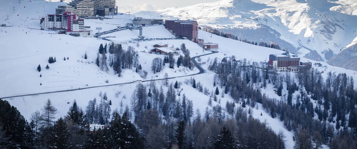 A snow-covered mountain town with ski slopes, buildings, and a prominent hotel.