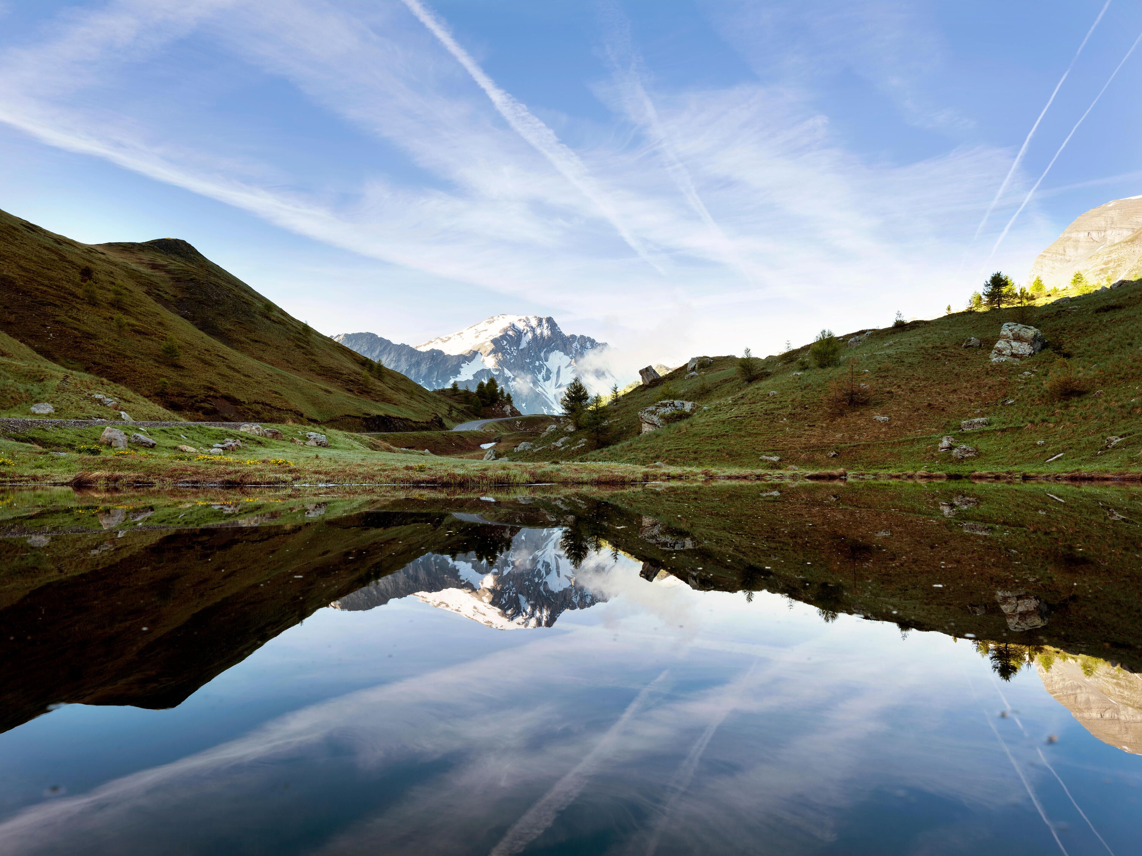 A mountain lake with reflections of the sky and distant mountains.