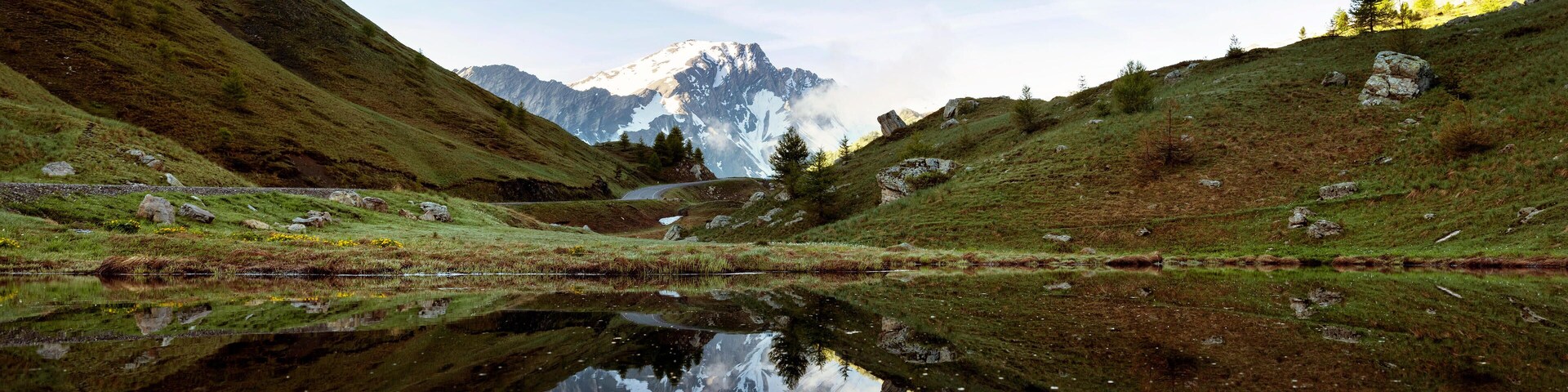 A mountain lake with reflections of the sky and distant mountains.