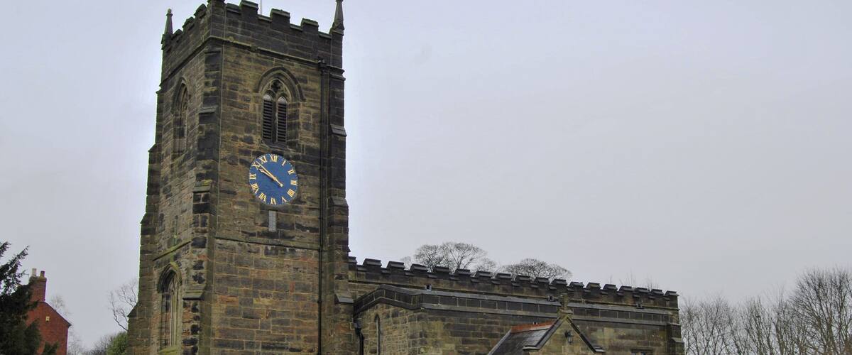 A historic church with a clock tower and a graveyard in front.