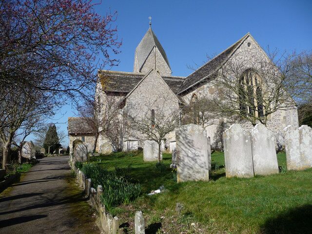 A church with a stone facade and a steeple, surrounded by a cemetery with headstones.