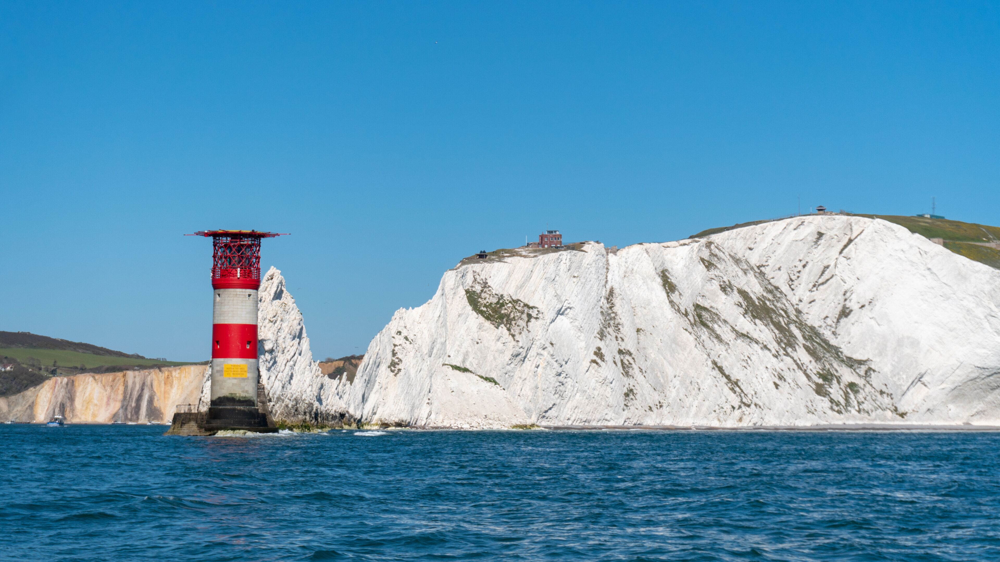 A lighthouse on a rocky cliff by the sea.
