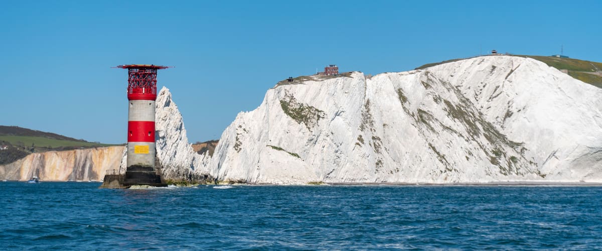 A lighthouse on a rocky cliff by the sea.