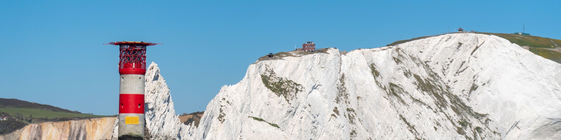 A lighthouse on a rocky cliff by the sea.
