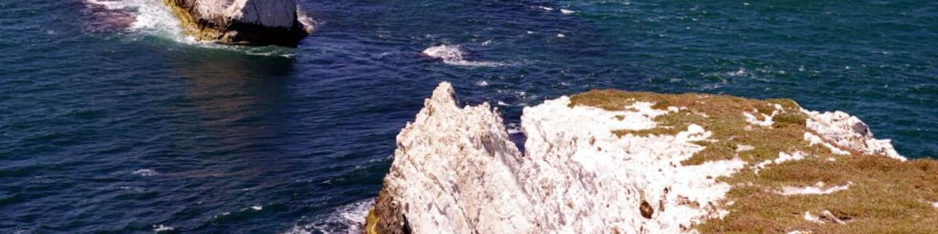 A rocky coastline with a lighthouse and a boat in the water.