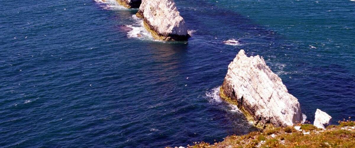 A rocky coastline with white cliffs and a red lighthouse.
