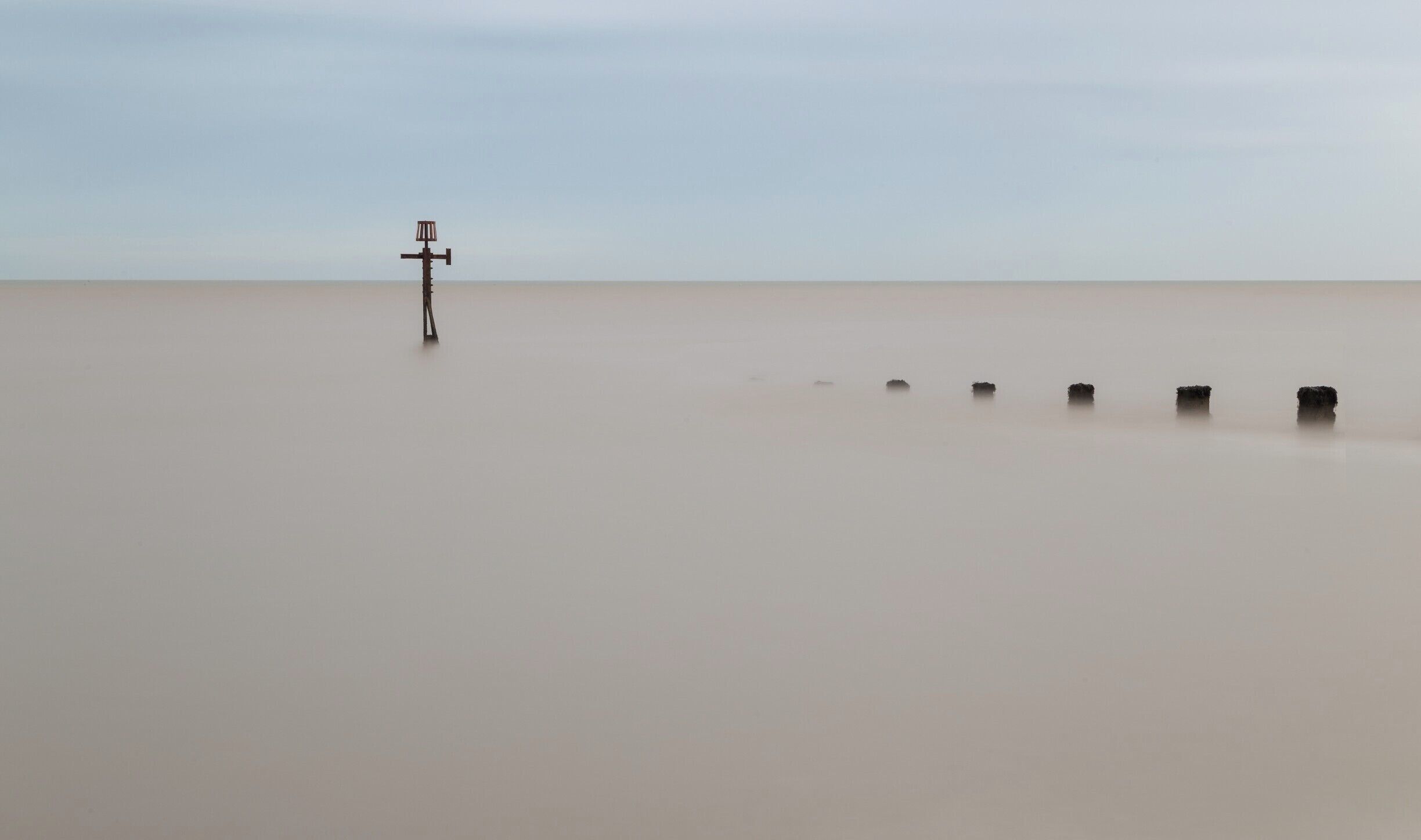 There a groynes all over the Norfolk coast.  Those are used a defences against erosion.  At least I believe this is what they were used for as most of them looks pretty old and I am not sure how effective they are nowadays.

I was amazed with how brown colour of the sea / channel was in the area.  Although I did not think initially this would make for good pictures, actually at sunrise in particular it turned to dark pink tints that contrasts nicely with a blue sky.