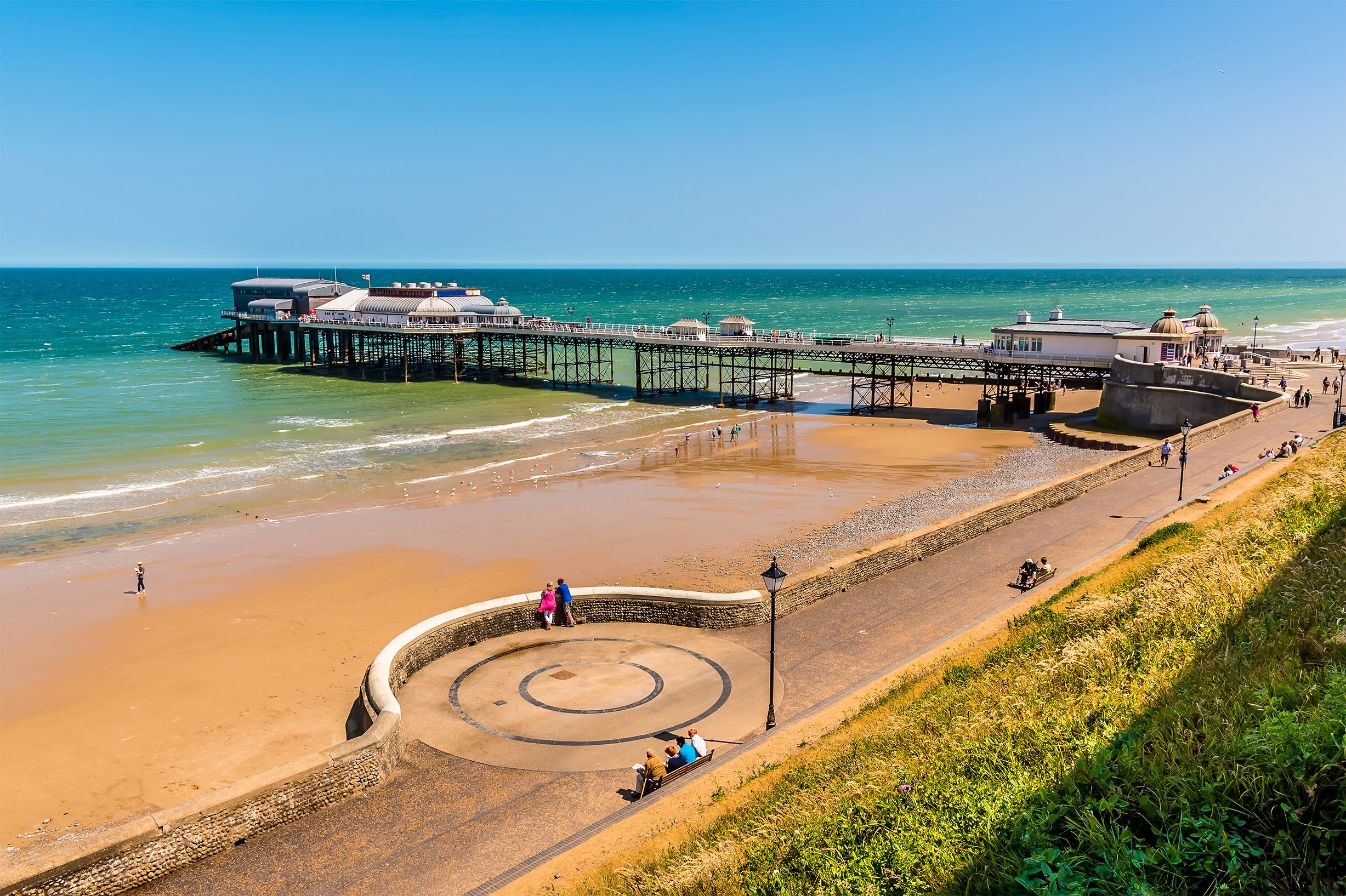 A coastal pier with a beach and promenade.