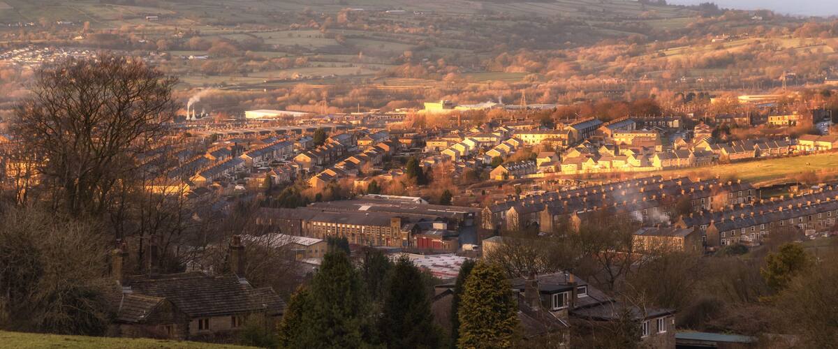 A town nestled in a valley with rolling hills in the background.