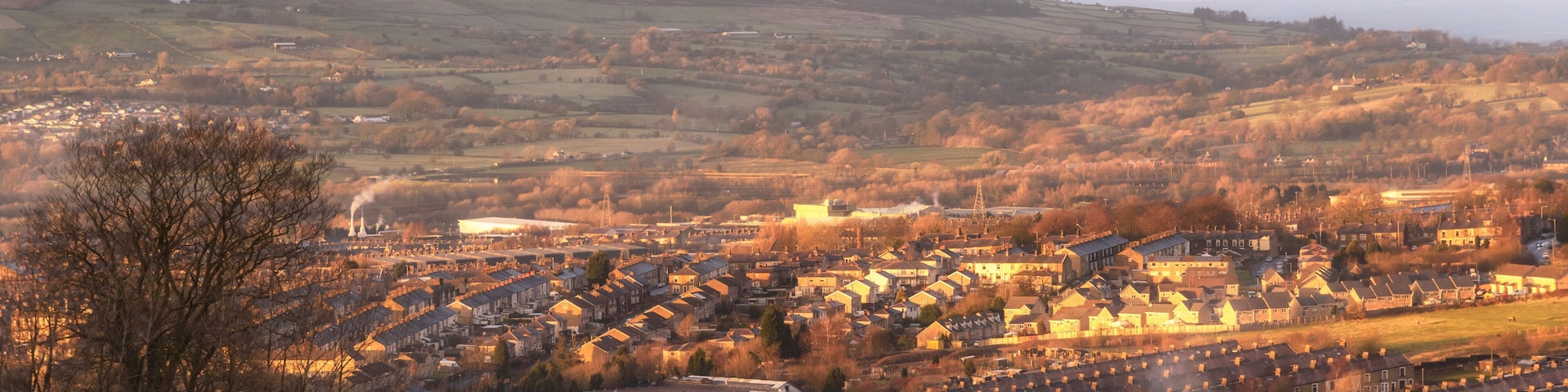 A town nestled in a valley with rolling hills in the background.