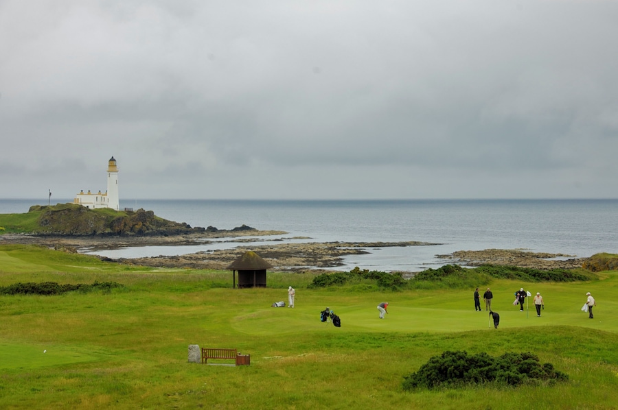 Un campo de golf con un faro, costa rocosa y vista al océano.