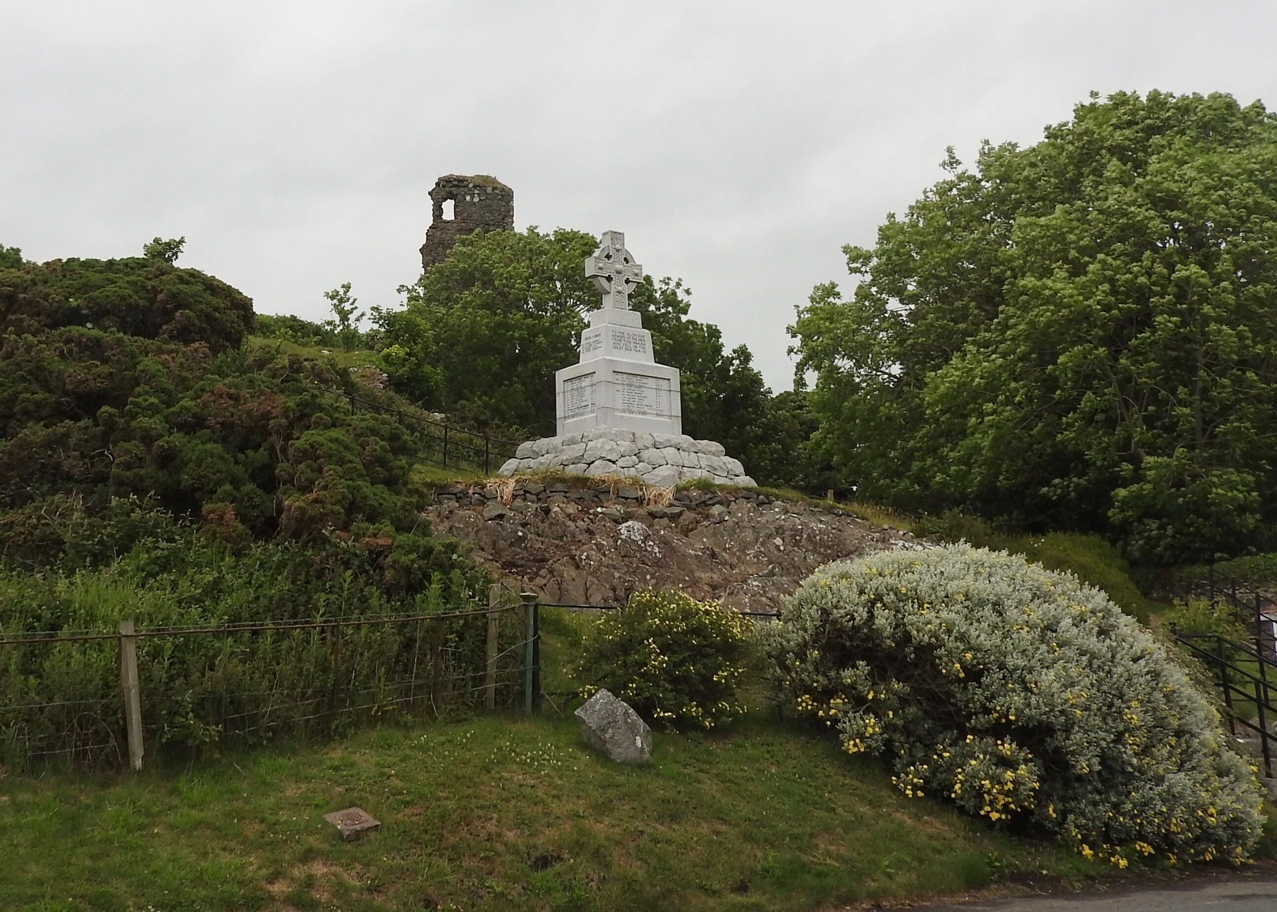 In the background is the only remnants of the Ardstinchair Castle remaining to this day. Ardstinchar Castle is a late medieval castle in the west coast of Ayrshire at the mouth of the River Stinchar. It was built by Hugh Kennedy of Ardstinchar in the mid-15th century. In the 1770s, the castle was demolished and the stone was used to build a bridge. In the middle is a war memorial. 