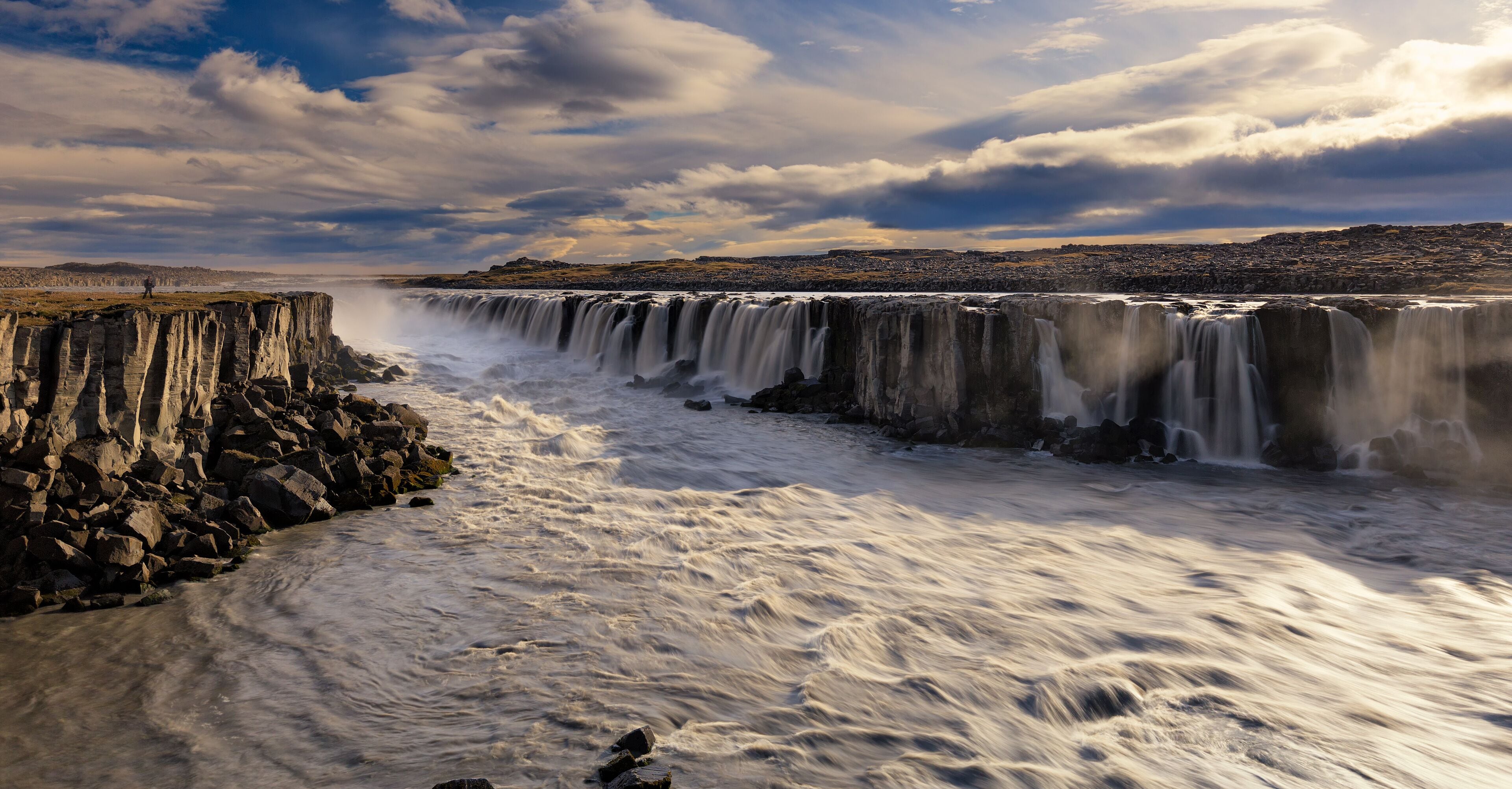 A waterfall cascading over a rocky cliff into a river.