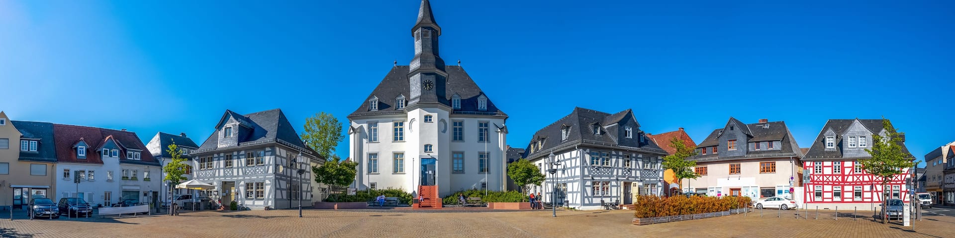 A town square with a prominent church, traditional half-timbered houses, and a cobblestone street.