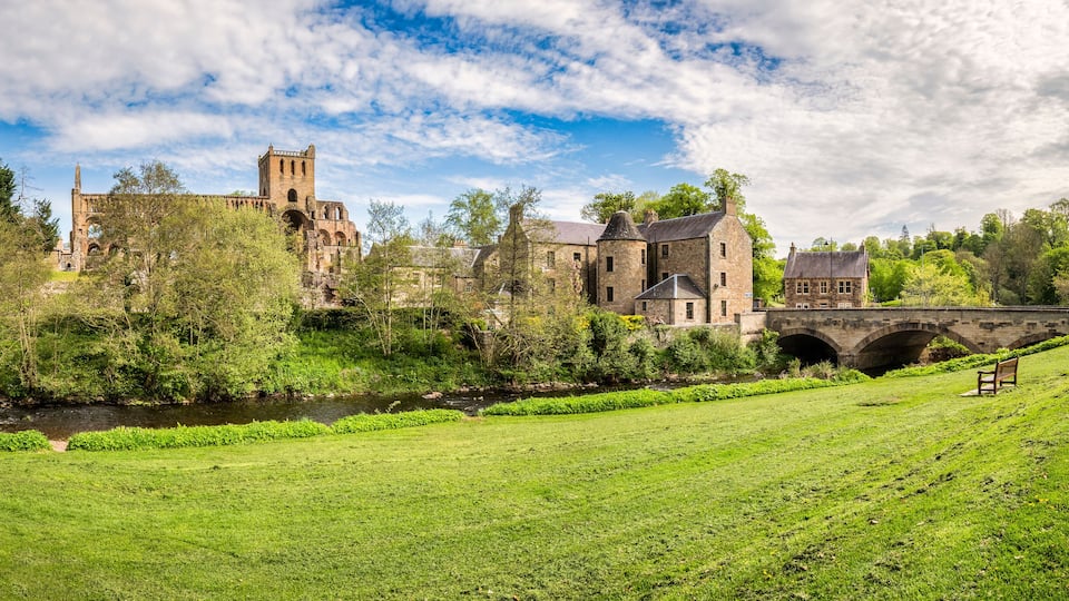 A historic castle with a tower, a river, and a bridge.
