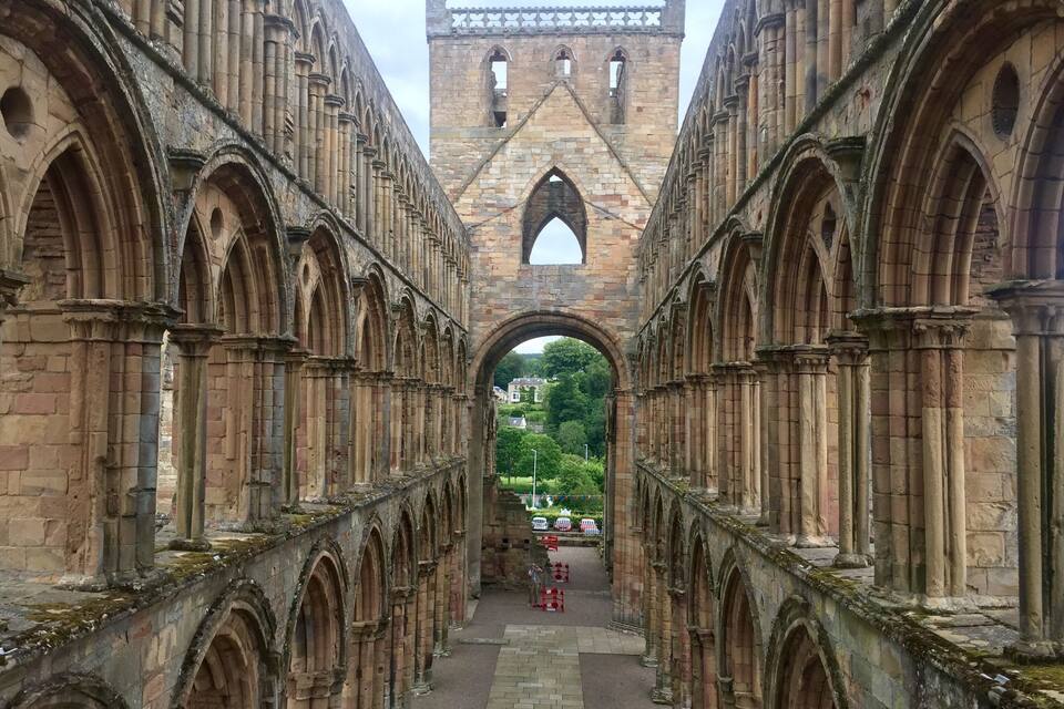 Una antigua estructura de piedra con paseos arqueados y una torre central.