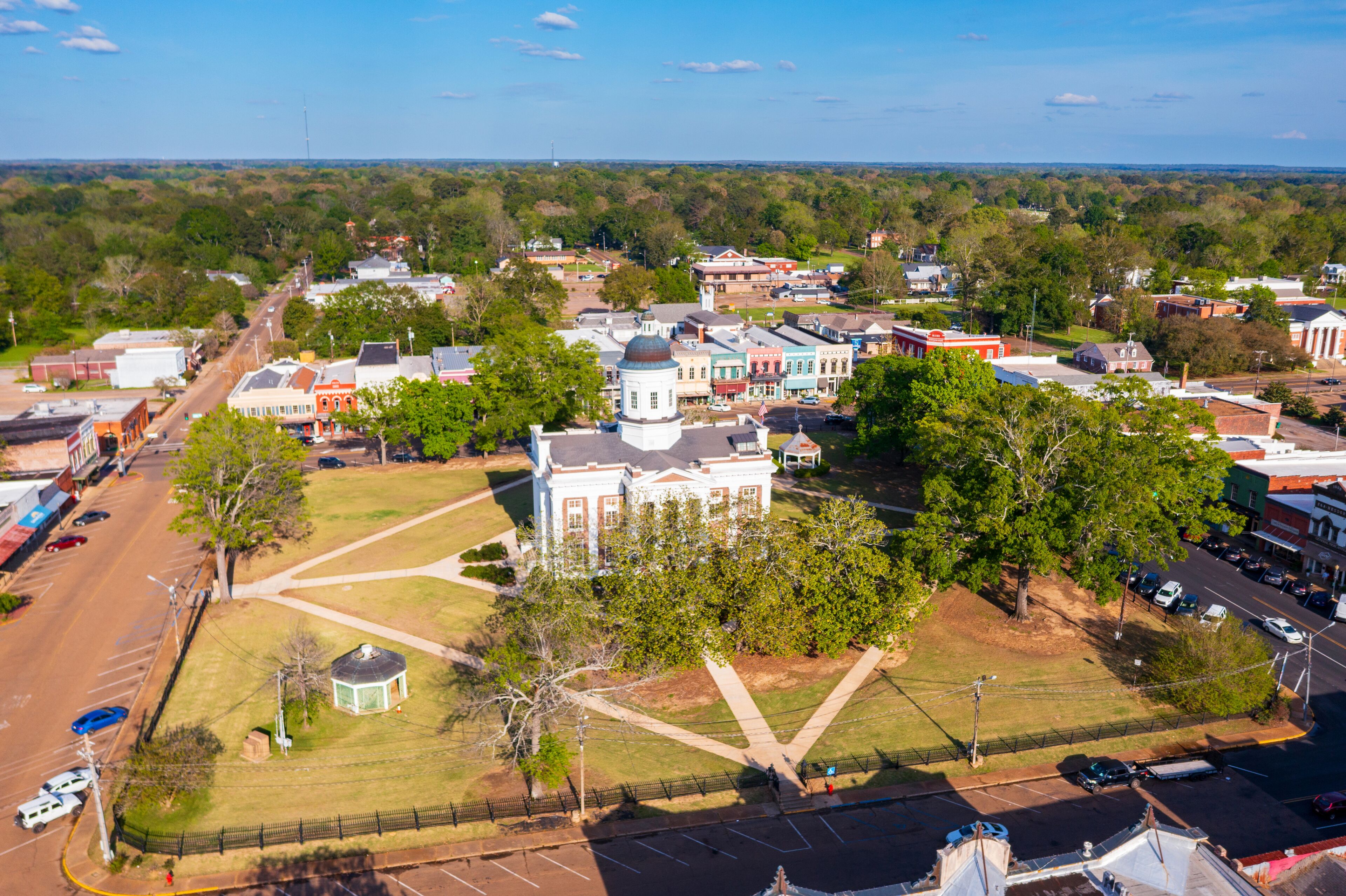 An aerial view of a town with historic buildings, a large white church with a dome, and a central square.