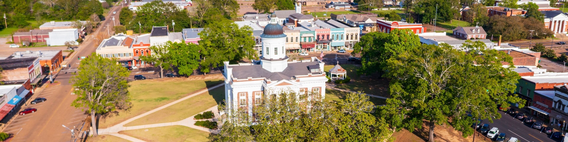 An aerial view of a town with historic buildings, a large white church with a dome, and a central square.