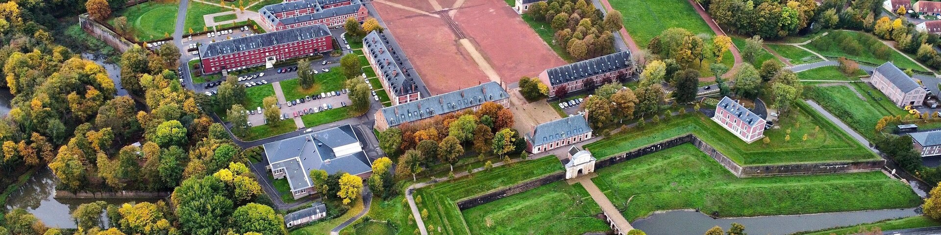 Vista aérea de una extensa propiedad con varias edificaciones, un campo deportivo y abundante vegetación.
