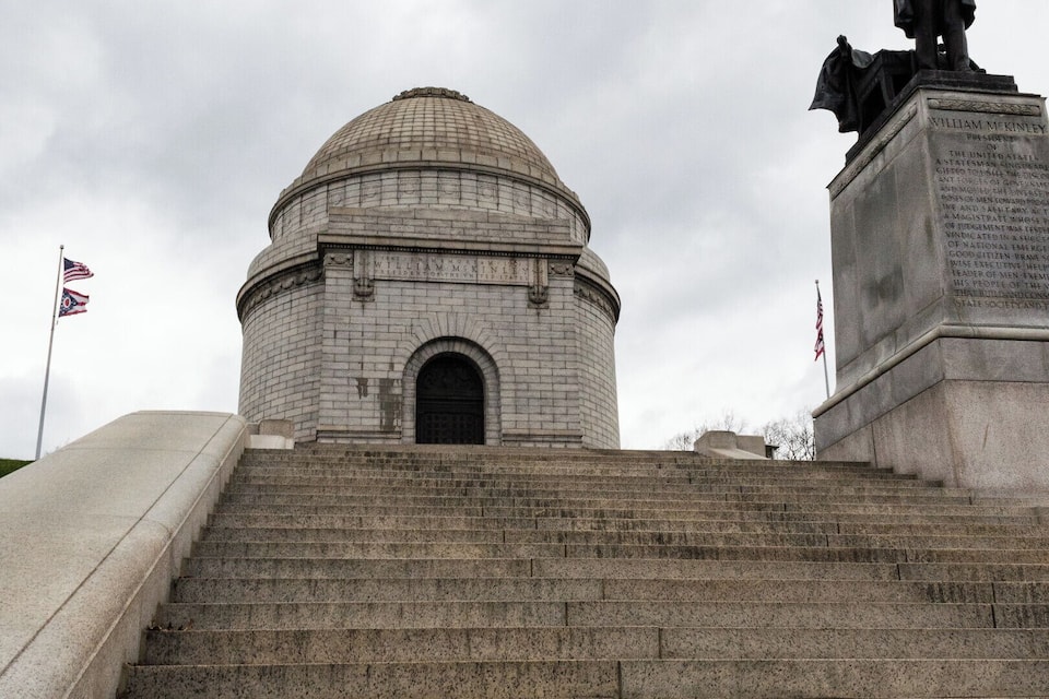 A stone staircase leading to a dome-shaped building with a statue on the right.