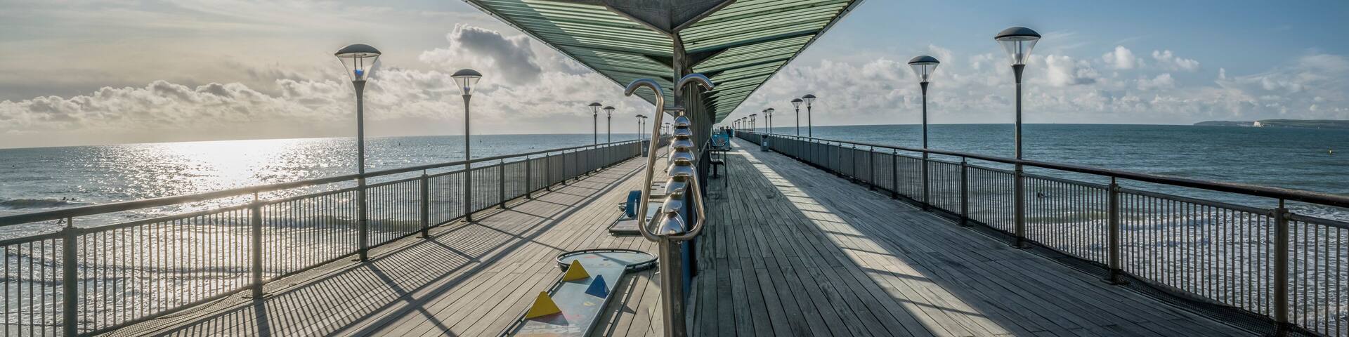 Empty Boscombe Pier at Bournemouth on a bright sunny day, sun lighting the pier on one side with shade on the other. Bournemouth, England, UK