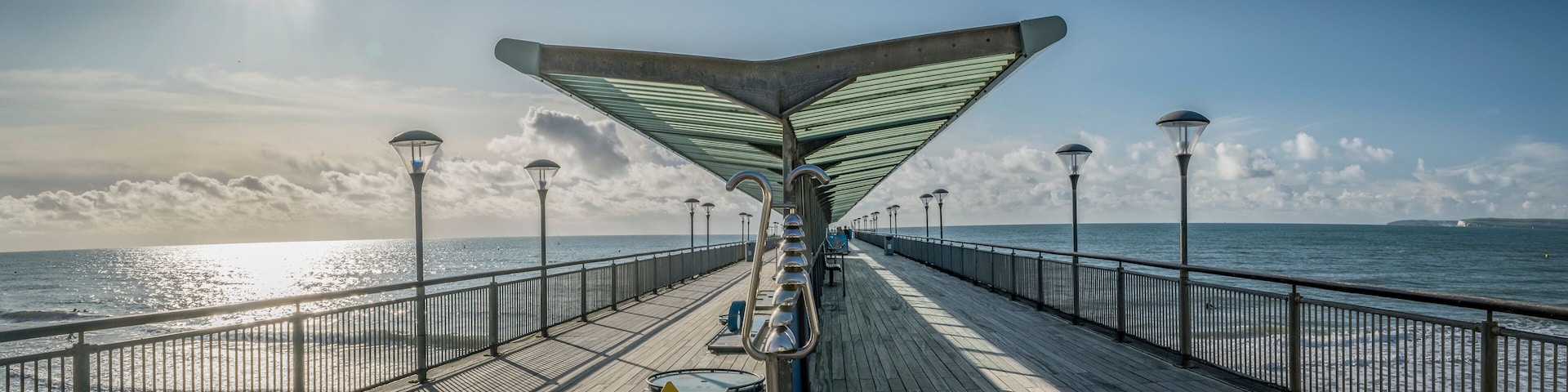 Empty Boscombe Pier at Bournemouth on a bright sunny day, sun lighting the pier on one side with shade on the other. Bournemouth, England, UK