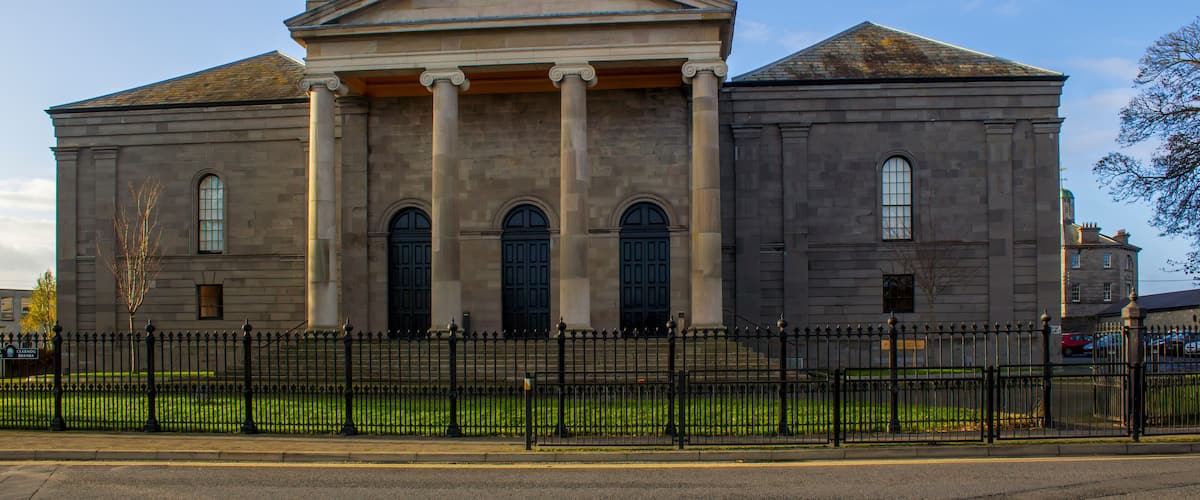 A large, historic building with a classical architectural style, featuring a prominent entrance with columns and a triangular pediment.
