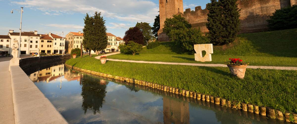 A castle, a canal, and surrounding buildings.