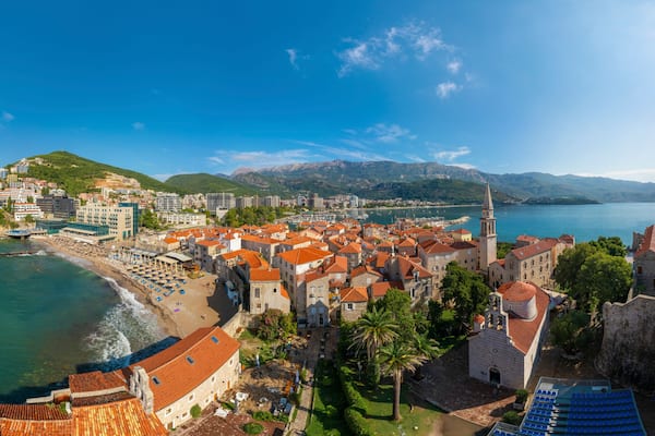 Une ville cĂŽtiĂšre dotĂ©e dâun fort historique, dâune plage et bordĂ©e par une chaĂźne de montagnes.