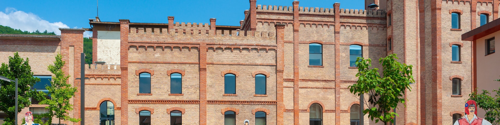 A historic brick building with arched windows and a turret.