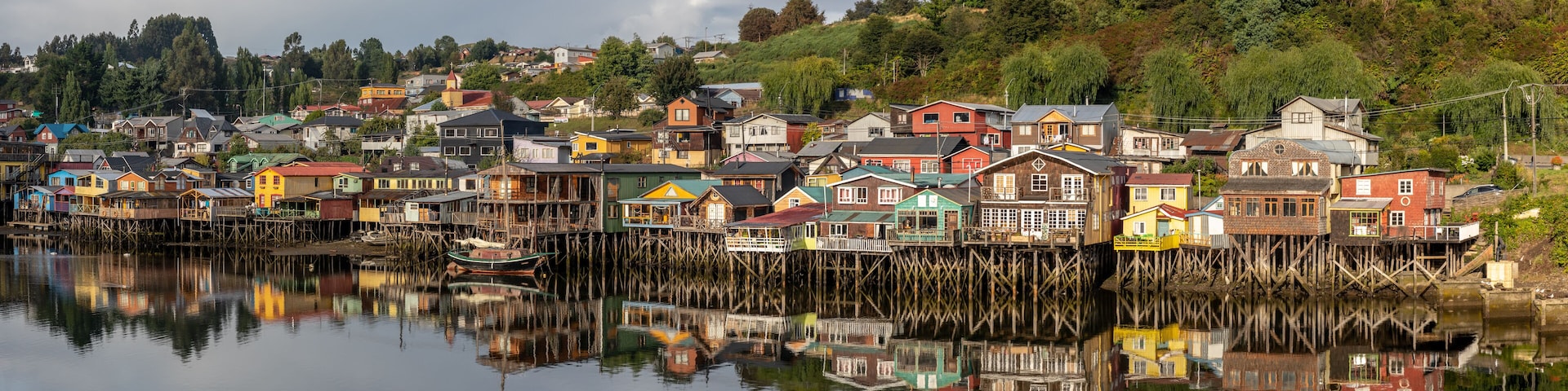Ein Panorama der Stadt von Castro auf Chiloé, mit den bunten, hölzernen Stelzenhäuser, welche sich im seichten Wasser spiegeln