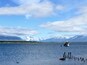 Ein ruhiger See mit einem kleinen Boot, das in der Nähe des Ufers vor Anker liegt, umgeben von Bergen und einem klaren Himmel.