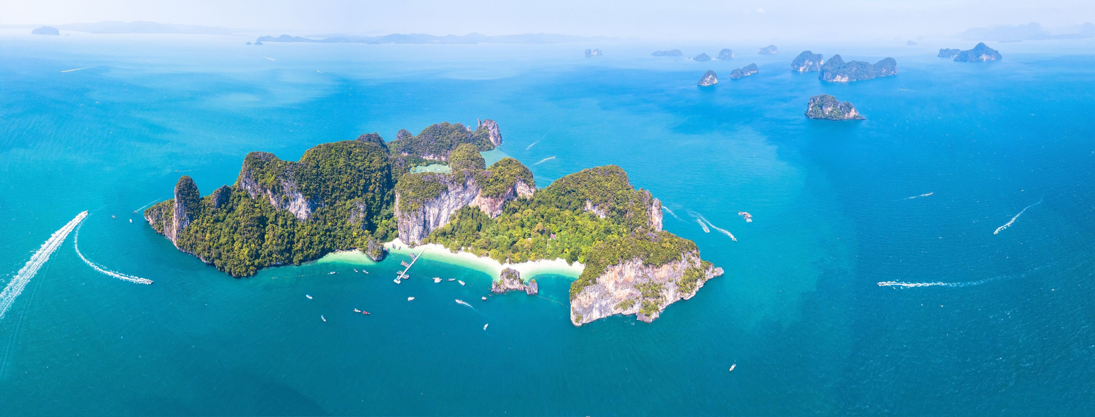 An aerial view of a lush, green island surrounded by turquoise waters, with several smaller islands in the distance.