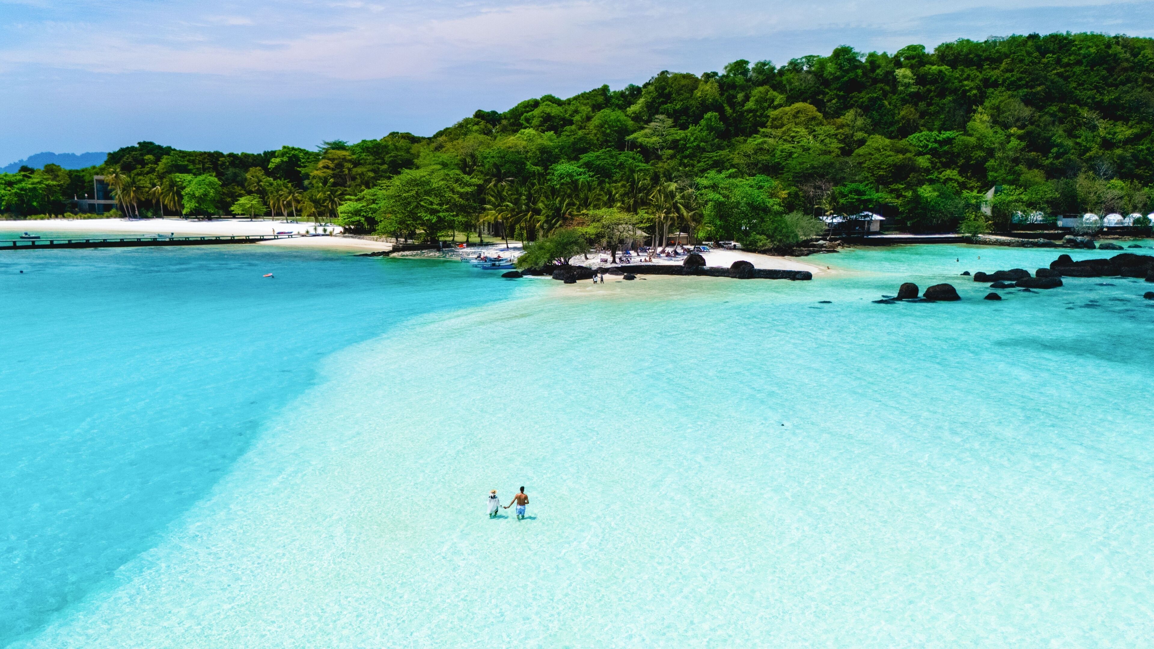 Beautiful turquoise waters invite visitors to explore the serene beach at a tropical paradise resort