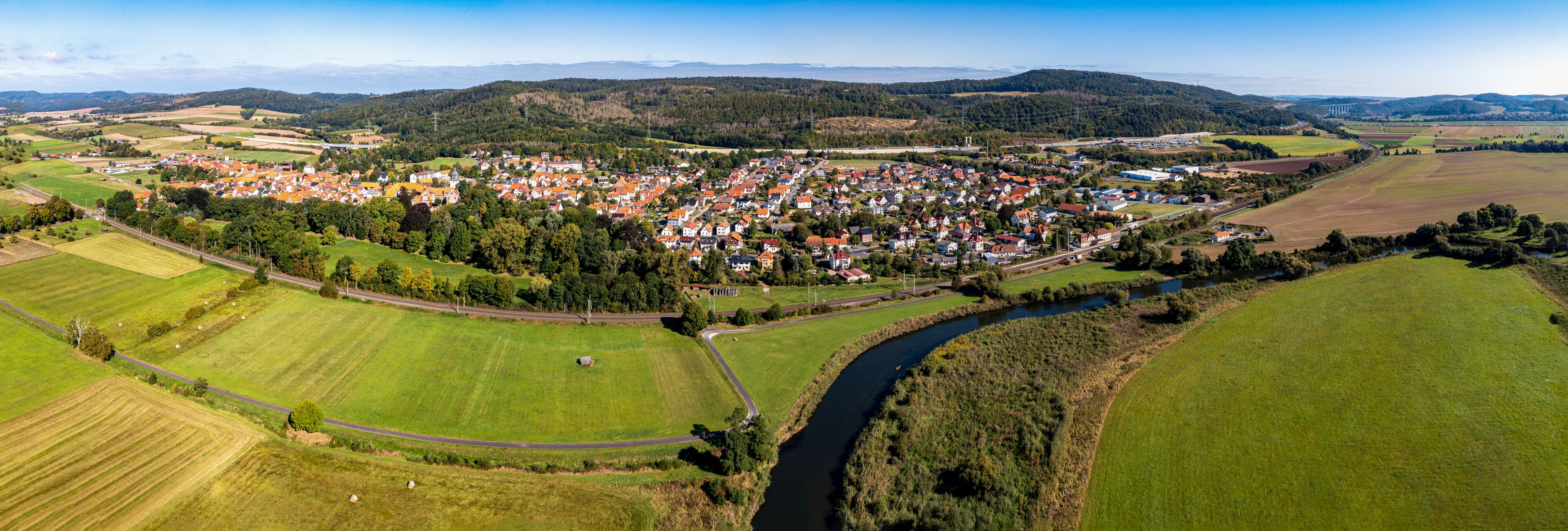 A rural town with a river, surrounded by fields and hills.