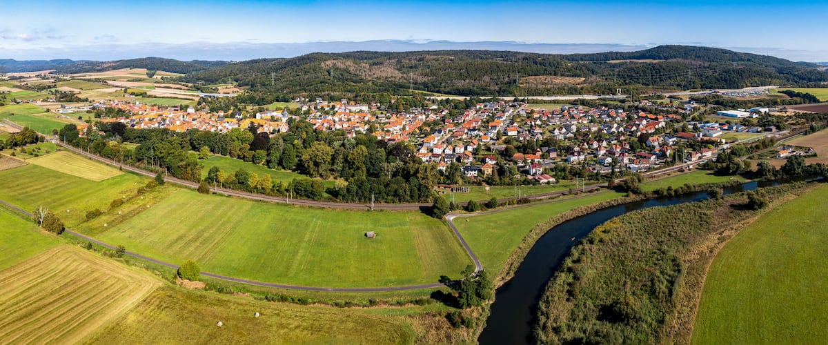 A rural town with a river, surrounded by fields and hills.