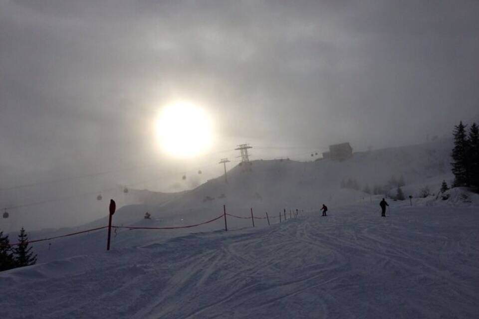 A snowy ski slope with a ski lift and a red fence.